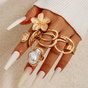 Detailed close-up of gold flower ring and baroque pearl ring set worn on model fingers