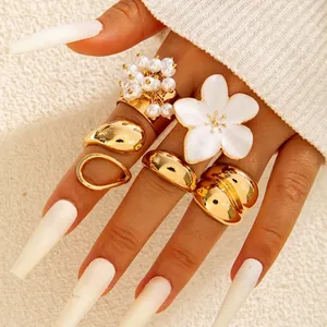 Close-up of gold-plated geometric ring set with Baroque pearls and white enamel flowers