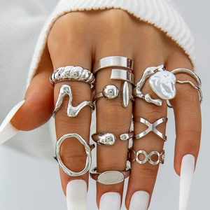 Macro detail of silver geometric rings set featuring baroque pearl and flower motifs