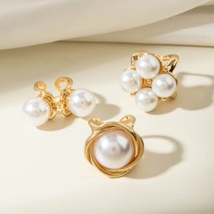 Detailed view of three baroque pearl rings with gold alloy flower and branch designs