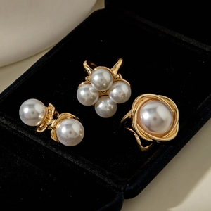 Close-up of baroque pearl jewelry set with gold floral branch rings in a black velvet box