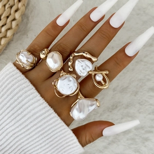 Close-up of a 5-piece gold Baroque pearl ring set worn on hand with white fur background