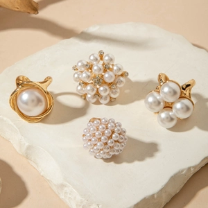 Close-up of four baroque pearl jewelry pieces on stone, showing gold metal and crystals