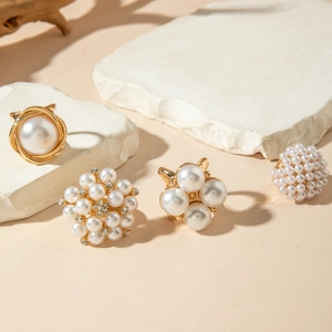 Macro shot of baroque pearl rings and floral alloy jewelry on white decorative stones