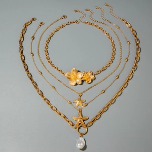 Detail of layered gold necklaces featuring starfish pendants and a large baroque pearl