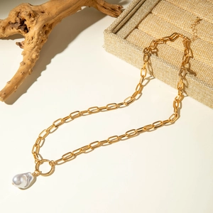 Detail of a gold paperclip chain necklace with a large white baroque pearl pendant