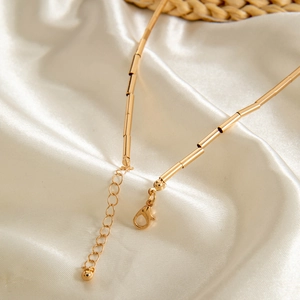 Close-up of golden bamboo link necklace with lobster clasp and adjustable extender chain