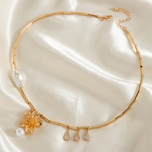 Close-up of gold flower pendant with baroque pearl and teardrop gems on satin