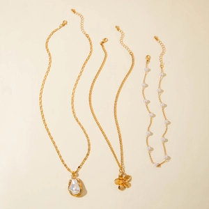 Detail view of a gold-tone jewelry set with starfish flower charms and white pearls