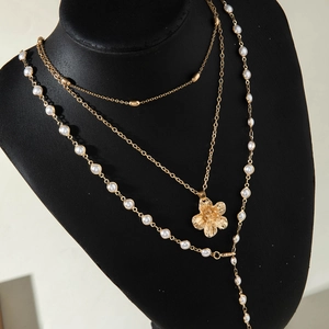 Detailed layered gold necklace with starfish flower pendant and pearls on black display