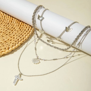 Detailed view of layered silver starfish and pearl necklaces on a white stand