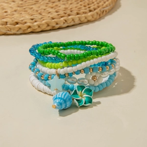 Detail of bohemian layered beaded bracelet featuring conch shells and floral pendants