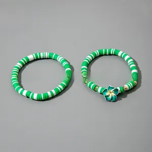 Détail de bracelets bohèmes en perles d'argile vertes et blanches avec fleur de frangipanier