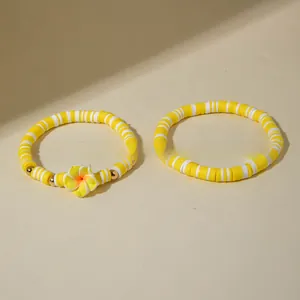 Gros plan de bracelets bohèmes en perles Heishi jaunes et blanches avec breloque