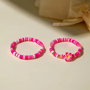 Détail de bracelets Heishi bohèmes rose et blanc avec pendentif fleur de frangipanier