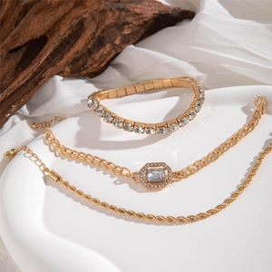 Vue détaillée de bracelets en alliage doré sertis de diamants carrés sur tissu blanc
