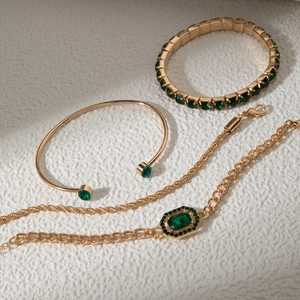 Détails de bracelets à chaîne dorée avec des pierres vertes de taille émeraude