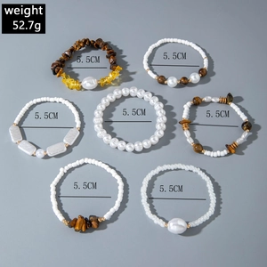 7-piece gold beaded bracelet set with tiger eye stones and pearls on grey background