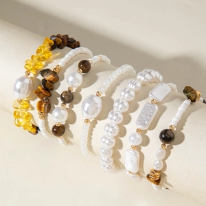Close-up of golden beaded bracelet set with faux pearls and natural amber stones