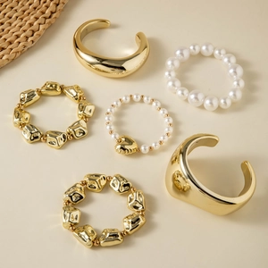 Detail of 6-piece jewelry set featuring liquid metal gold cuffs and pearl heart bracelets