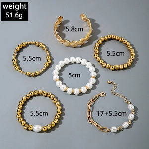 Detailed view of a 6-piece gold bead and pearl bracelet set with a seashell texture bangle