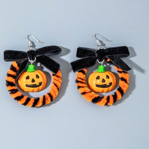 Detail van Halloween pompoen oorbellen met fluwelen strikken en gestreepte chenille ringen