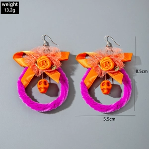 Detail van paarse pluchen pompoen oorbellen met oranje rozen en schedel bedeltjes