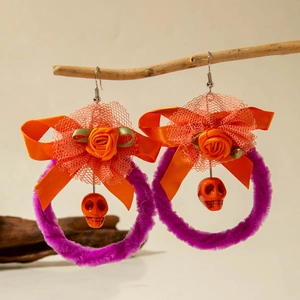 Detail van paarse pluche Halloween pompoen oorbellen met strikjes op een houten tak