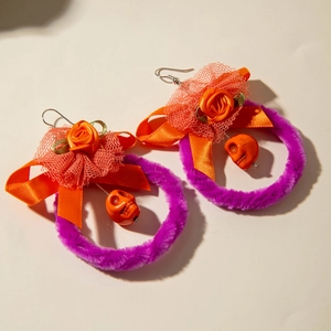 Detail van Halloween-oorbellen met paarse pluche ring, oranje strik en schedelbedeltjes