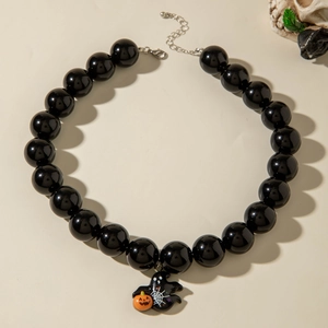 Macro detail of Halloween necklace featuring black beads and ghost pendant with pumpkin charm