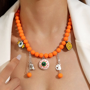 Close-up of Halloween necklace with orange beads, pumpkin, and ghost charms on a model