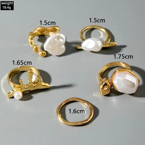 Detailed view of 5-piece gold alloy ring set with irregular pearls and wavy texture
