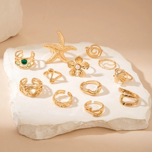Detail of 11-piece gold alloy rings set featuring starfish, flowers, and green gemstones