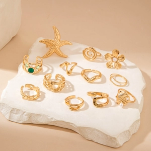 Macro detail of 12pcs gold sea star and shell rings with pearls on white stone