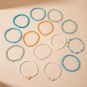 Detail of 13-piece bohemian bead bracelets with starfish charms on beige background