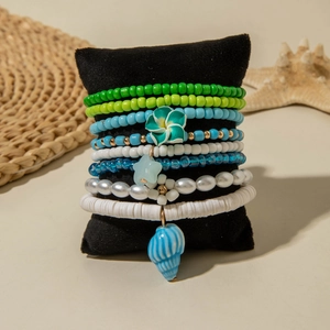 Detail of stacked bohemian beaded bracelets with summer flower and seashell charms