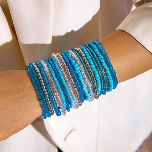Close-up of bohemian layered beaded bracelets in blue and silver tones on a wrist