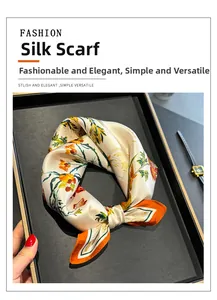 Détail macro d'un foulard carré en soie avec imprimés floraux sur un plateau élégant