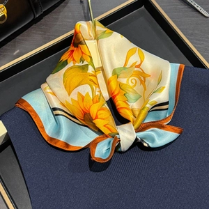 Élégant foulard en soie à imprimé tournesol noué sur le col d'un pull bleu foncé