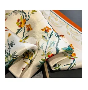 Détail d'un foulard en soie à motif rétro montrant la texture satinée et l'ourlet orange