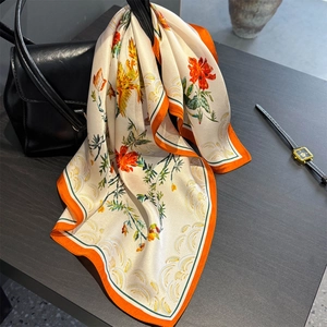 Élégant foulard en soie à fleurs avec bordure orange attaché à un sac à main en cuir
