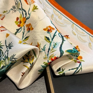 Détail du foulard en soie montrant la texture satinée et les motifs floraux élégants