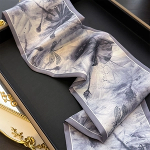 Gros plan sur un foulard en soie avec imprimé libellule gris et bords roulés blancs fins