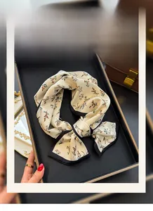 Dettaglio di una sciarpa in seta con motivi floreali e bordo nero a contrasto chic