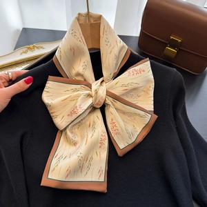 Elegante foulard in seta con stampa di grano annodato a fiocco su maglione nero