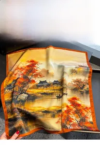 Detail eines Seidenschals mit orangefarbener Chinamalerei auf einer schwarzen Ledertasche