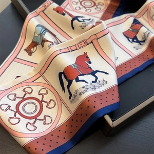 Detailed view of the equestrian pattern silk scarf with horses and buckle motifs
