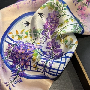 Close-up of silk scarf with lavender floral patterns and elegant swallow bird print