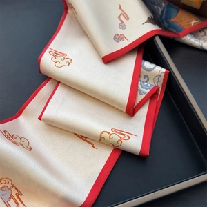 Détail d'un foulard en soie twilly aux motifs de nuages et bordures rouges