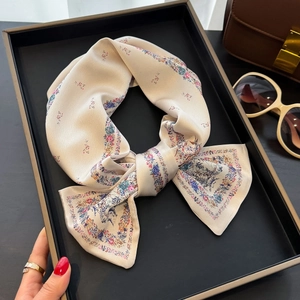 Foulard in seta con stampa floreale e ritratto classico, annodato a fiocco in vassoio